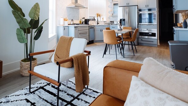 Una cocina moderna con electrodomésticos de acero inoxidable, un comedor con mesa y sillas, y una sala de estar con sofá y una mesa de centro.