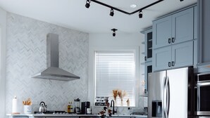 Una cocina moderna con una isla central, gabinetes grises y electrodomésticos de acero inoxidable.