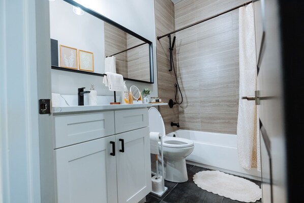 Un baño moderno con inodoro, lavabo y zona de ducha.