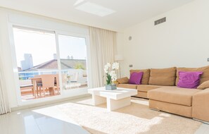 Relax in this stylish living room with a sliding glass door leading to a city view, a comfortable sofa, and a cozy coffee table.
