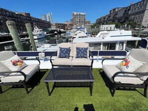 A rooftop terrace with two lounge chairs, a small table, and a view of the marina with boats and buildings. - Endless Summer: Oceanside Views (Boston)