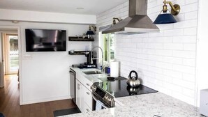 A modern kitchen with a built-in stove, oven, and microwave, a large window, and a flat-screen TV mounted on the wall. - Endless Summer: Oceanside Views (Boston)
