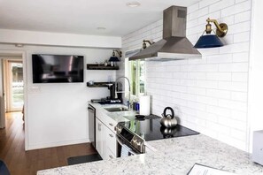 A modern kitchen with a built-in stove, oven, and microwave, a large window, and a flat-screen TV mounted on the wall.