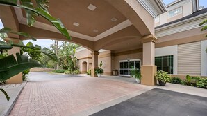 A hotel entrance with a covered walkway, potted plants, and a glass door entrance. - Suites at Lake Buena Vista close Disney Springs with free parking (Orlando)