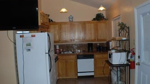 A compact kitchen with wooden cabinets, a white refrigerator, a microwave, and a sink. There are two pendant lights above the counter. - 123 West Harbor Condo B - Beautiful Condo in the harbor with spacious deck (Port Mansfield)