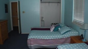 A bedroom with a bed, a dresser, a closet, and a window with blinds. - 123 West Harbor Condo B - Beautiful Condo in the harbor with spacious deck (Port Mansfield)