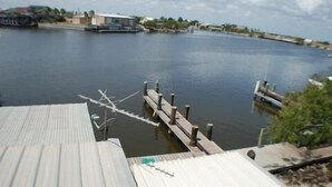 A view of a dock extending into calm water, with a building in the background. - 123 West Harbor Condo B - Beautiful Condo in the harbor with spacious deck (Port Mansfield)