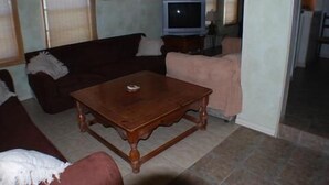 A living room with a wooden coffee table, a dark-colored sofa, a light-colored sofa, and a television on a stand. - 116 Southshore - Cute little hideaway, ready for the all around fishing (Port Mansfield)