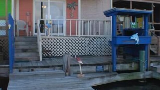 A multi-story building with a wooden dock leading to a pool.
