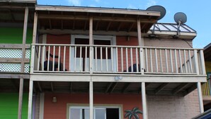 A two-story building with a balcony, a satellite dish, and a wooden deck.