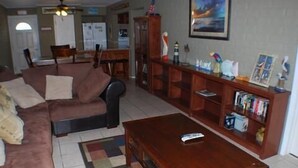 A living room with a brown sofa, a wooden coffee table, and a bookshelf.