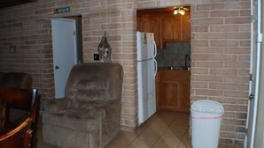 Une petite cuisine équipée d’un réfrigérateur, d’un meuble en bois et d’une chaise.