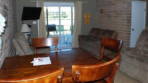 Un coin repas avec une table et des chaises en bois, un téléviseur et un mur en briques.