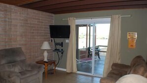 Un salon avec un mur en briques, un téléviseur à écran plat, une lampe et un canapé.