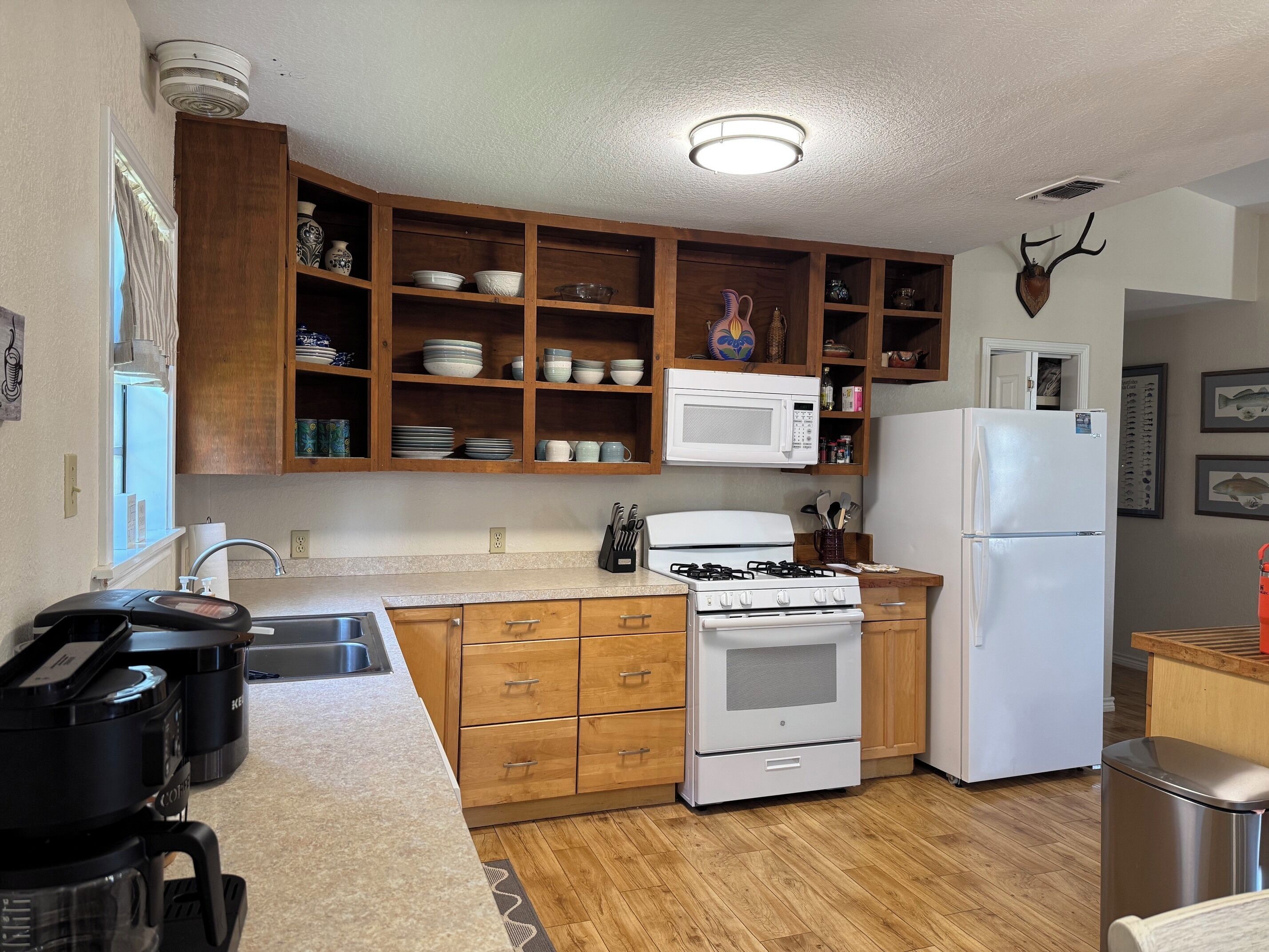 Una cocina con gabinetes de madera, microondas, estufa y refrigerador.