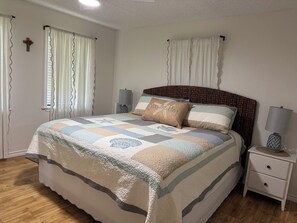 A bedroom with a bed, nightstands, a lamp, and curtains. - 309 Beach - Cute getaway home away from home! (Port Mansfield)