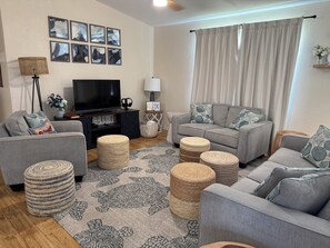 A living room with a grey sofa, a television, and a patterned rug. - 309 Beach - Cute getaway home away from home! (Port Mansfield)