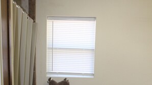 A bathroom with a toilet, a window, and a towel hanging on the wall.
