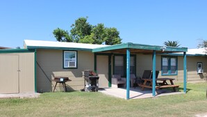 A single-story building with a covered patio area, a barbecue grill, and outdoor seating.