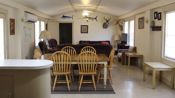 A dining area with a wooden table and chairs, a sofa, and a ceiling fan.