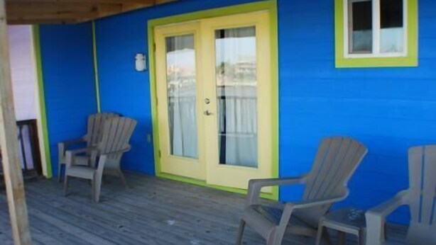A wooden deck with two chairs and a door with a yellow frame. - Fabulous Fisherman's Condo! (Port Mansfield)