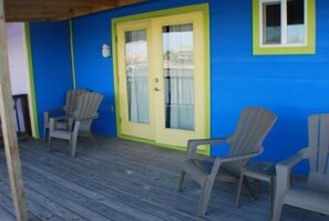 A wooden deck with two chairs and a door with a glass panel.
