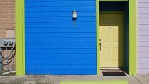 A two-story building with a blue exterior and a yellow door. - Fabulous Fisherman's Condo! (Port Mansfield)