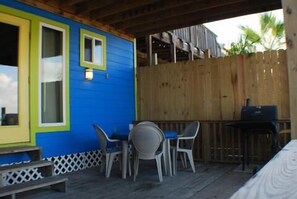 A covered outdoor seating area with a wooden deck, a table with chairs, and a grill. - Fabulous Fisherman's Condo! (Port Mansfield)