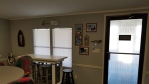 A kitchen with a dining table, bar stools, and a refrigerator.