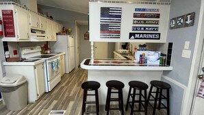 A compact kitchen with a central island, stools, and a flag-themed sign.