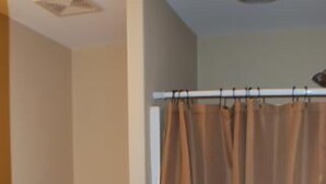 Ein Badezimmer mit Toilette, einer Duschvorhang und einer Toilettenpapierrolle auf dem Boden.