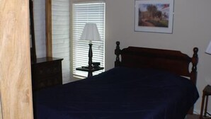 Ein Schlafzimmer mit Bett, Nachttisch, Lampe und einem Gemälde an der Wand.