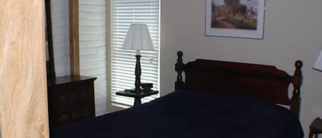 Un dormitorio con una cama, una mesita de noche, una lámpara y un cuadro en la pared.