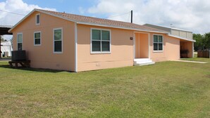Une maison de plain-pied avec un toit en pente, un porche à l’avant et un petit garage attenant.