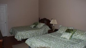 Une chambre avec deux lits, une table de chevet avec une lampe et une porte.