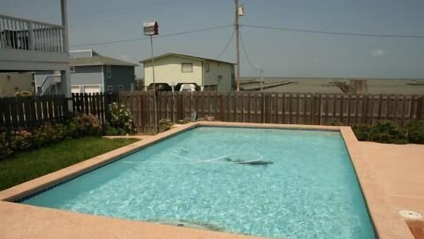 Une piscine rectangulaire à l’eau d’un bleu cristallin, entourée d’une terrasse en bois et d’un petit muret en briques.