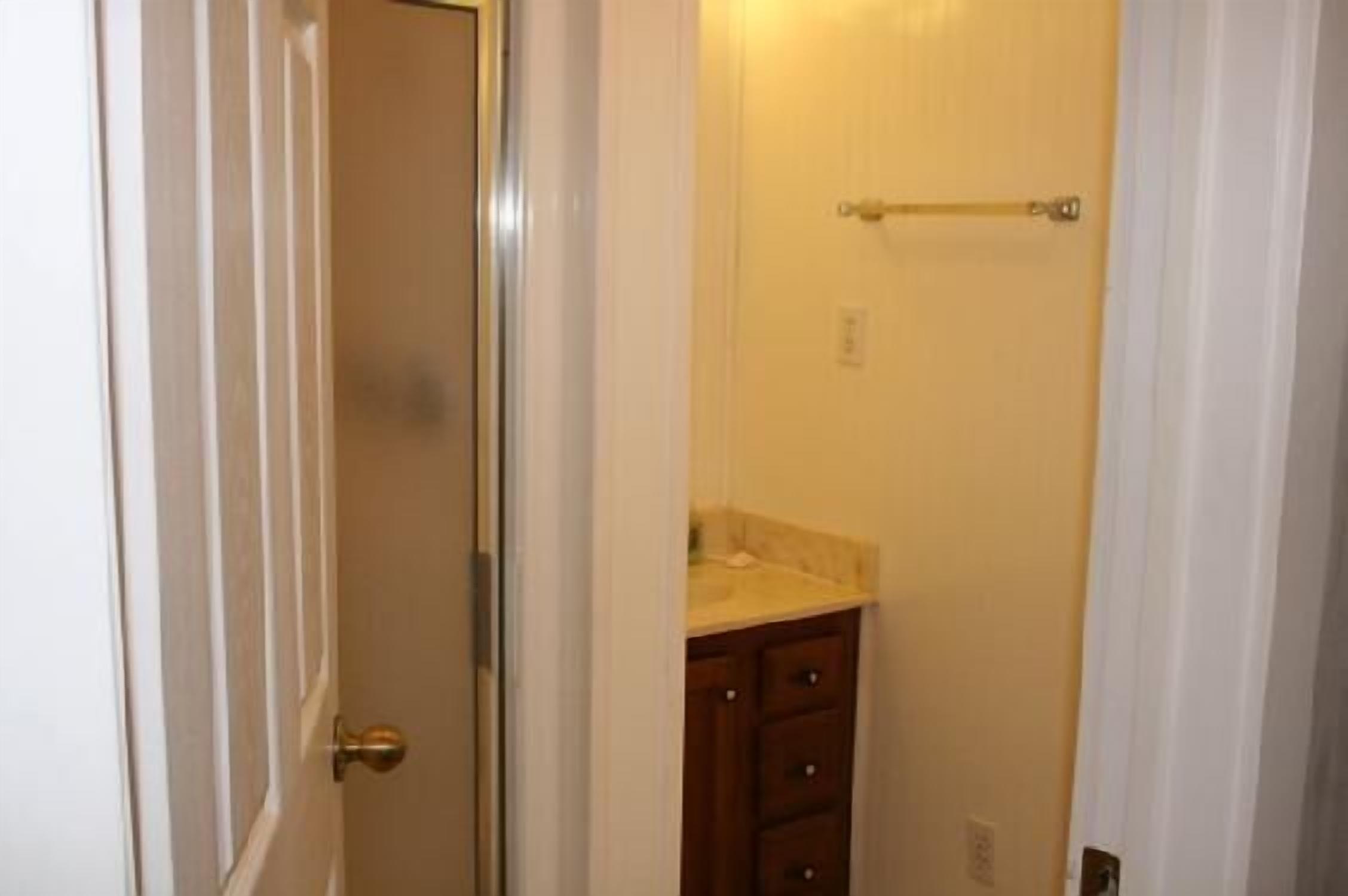 A bathroom with a white door, a towel rack, and a wooden cabinet.