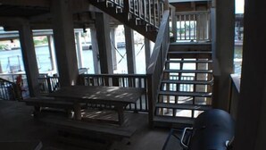 Un espace extérieur abrité, avec une table et des bancs en bois, un escalier et une vue sur l’eau.