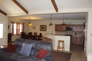Relax in this open-plan living space featuring a sofa, dining area, and kitchen with a microwave and island.