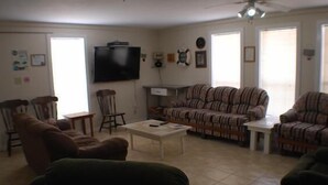 Un salon comprenant un canapé, une table basse, un téléviseur et un ventilateur de plafond.