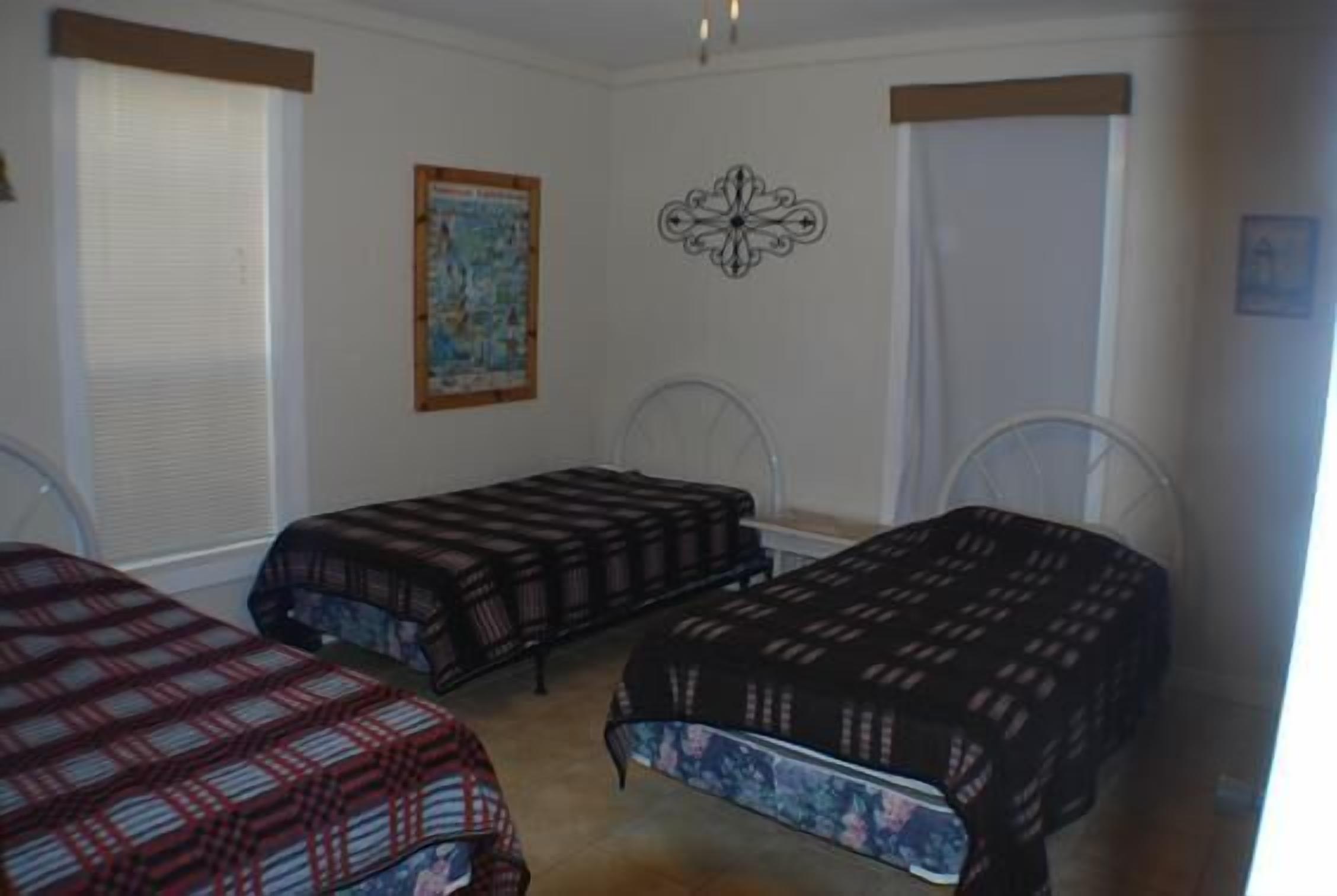 A bedroom with two single beds, a map on the wall, and a decorative wall piece.
