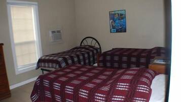 A bedroom with two beds, a window, and a poster on the wall.