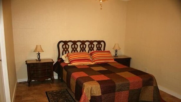 A bedroom with a wooden headboard, a quilted bedspread, two bedside tables with lamps, and a rug on the floor. - Knots Landing #2 - Newly remodeled 2 Bedroom/2 Bath (Port Mansfield)