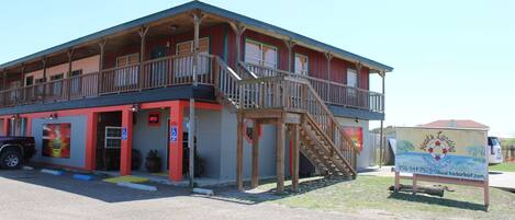 A two-story building with a balcony, a staircase, and a signboard.