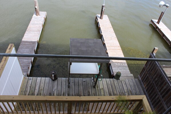 A wooden dock with a table and chairs, a hose, and a lamp post.
