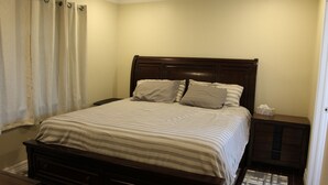 A bedroom with a bed, wooden headboard, bedside tables, and a nightstand. - 200 North Shore - Cozy Waterfront Cottage! Excellent Fishing! (Port Mansfield)