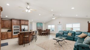 Amplia sala de estar con una mesa de comedor, cocina y un sofá grande color aguamarina.