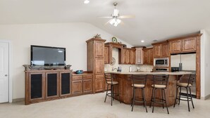Una cocina moderna con armarios de madera, una isla central con taburetes de bar, un microondas y un refrigerador.