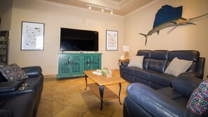 Un salon doté d’un téléviseur à écran plat, d’un meuble de couleur turquoise et d’une grande fresque représentant des poissons sur le mur.