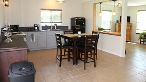 A modern kitchen with a dining area, featuring a refrigerator, cabinets, and a dining table with chairs. - 201 Matagorda - Cozy, Spacious Newly Remodeled Getaway! (Port Mansfield)